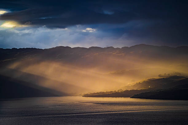 Golden sun creating dramatic light rays over a mountain range and still water