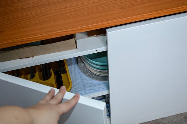 istock Open kitchen cabinet with dishes, utensils, and trays visible under a newly installed wooden countertop. Home organization, kitchen storage, renovation, DIY theme. 2254809346