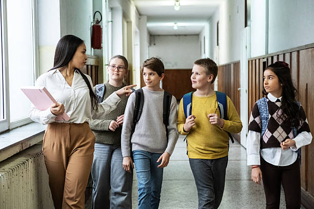 istock The teacher walks through the school lobby while speaking with her students as class is about to begin. 2254810221