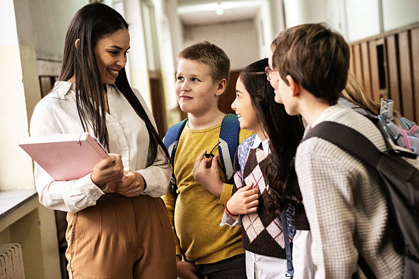istock The teacher walks through the school lobby while speaking with her students as class is about to begin. 2254810231