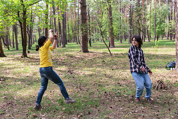 Mother and teen son playing together and laughing in forest during active outdoor family time