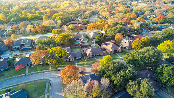 istock Parallel residential streets along multiple homes feature swimming pools, patio, framed by fall-colored trees. Upscale suburban houses with wooden fences, driveway patterns in Coppell, Dallas, TX 2254810705