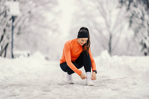istock Young woman tying shoe laces before winter run 2254812362