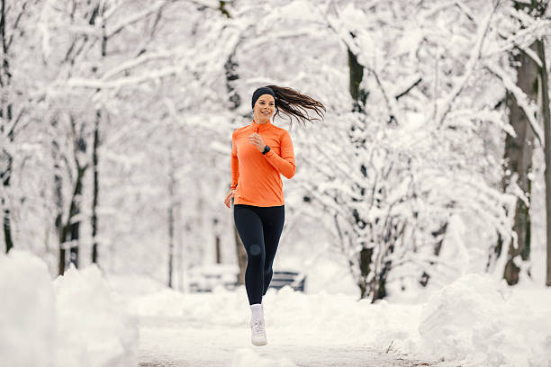 istock Woman running through snowy park during winter exercise 2254812373