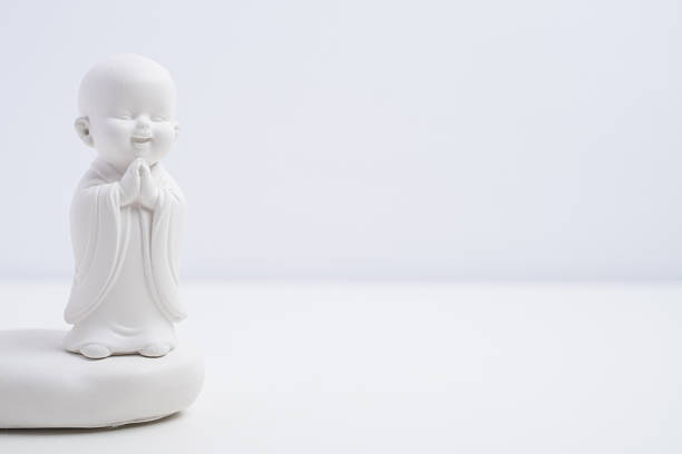 White buddha figurine with burning candle on white background. Zen meditation concept.