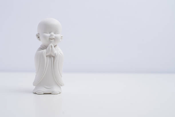 Zen spirituality. Small smiling Buddha monk figurine on white background