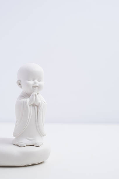 Zen spirituality. Small smiling Buddha monk figurine on white background