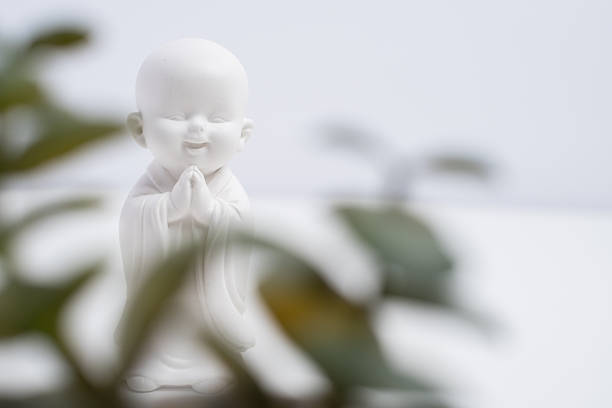 Zen spirituality. Small smiling Buddha monk figurine on white background