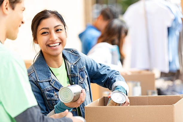 istock Happy young adults and multiracial group volunteering together sorting canned goods in boxes for a charity event. 2254814129