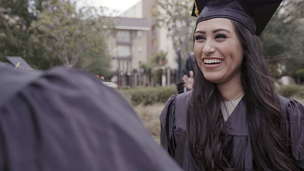 istock Young graduate smiles happily while celebrating her academic achievement outdoors with friends. 2254815365