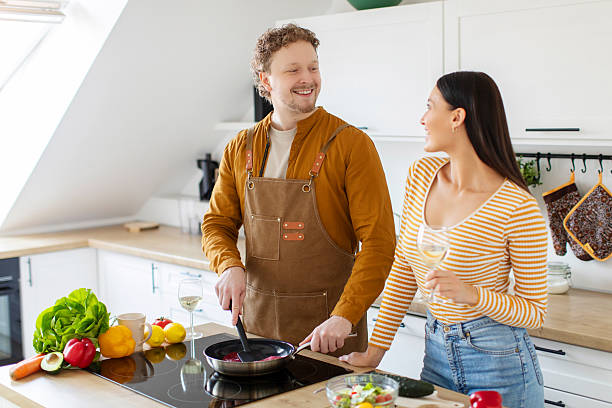 istock Loving spouses cooking together and talking while man making dinner and woman drinking wine in modern kitchen interior, copy space 2254819666