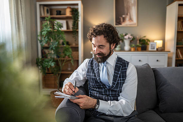 istock Man writing notes on notebook in living room 2254821215