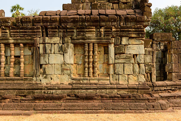 Close-up of weathered sandstone blocks and carved window columns at Bakong temple in Cambodia. The ancient stonework is highlighted by warm daylight, revealing intricate textures and subtle color variations.