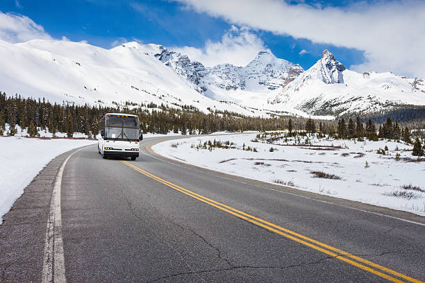Coach bus drives on the Icefields Parkway in the Canadian Rockies, Canada, during winter.