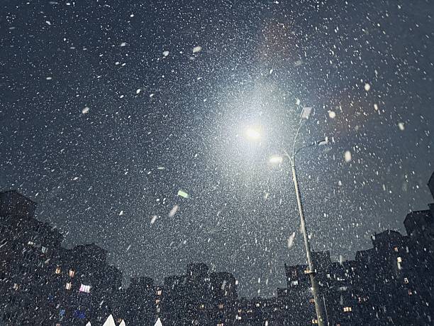 istock Nighttime Snowfall Over City Rooftops, Falling Snow Illuminated Beneath Streetlights In Urban Darkness, Dark City Skyline With Snowflakes Reflecting Light And Cold Atmosphere 2254823068