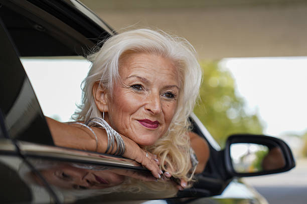 istock Stylish senior woman posing through car window 2254823309