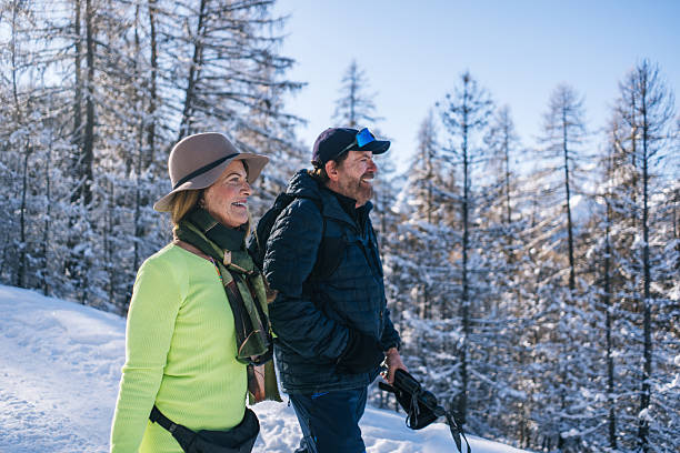 Senior couple walk snowy pathway on sunny, winter day, Sauze d'Oulx, Piedmont