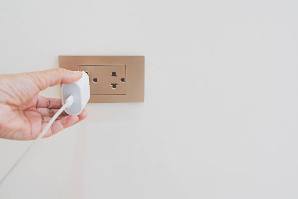 istock close up hand plugging adapter charge the battery with outlet socket on white concrete wall , for electric safety concept 2254829406