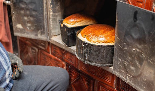 Steam is coming out of a professional oven in a bakery with bread proofing baskets stacked on top