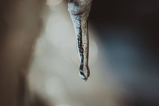 Icicles in the city close-up. Long icicle with selective focus. Winter. Frosty weather. Frozen water in winter, close-up. Icicles against the background of blurred buildings
