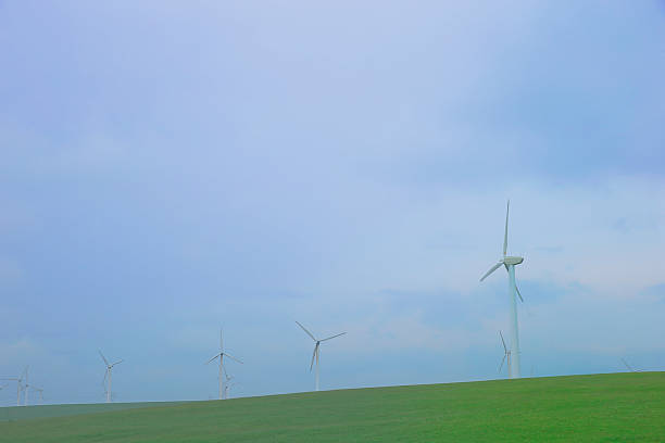 Windmills aerial view. Renewable energy. Large wind turbines with blades in field bright Green grassland.