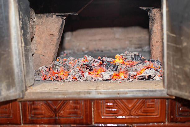 Hot glowing embers spread across the floor of a wood fired brick oven. Traditional oven heat background used for bread baking and rustic cooking concepts.