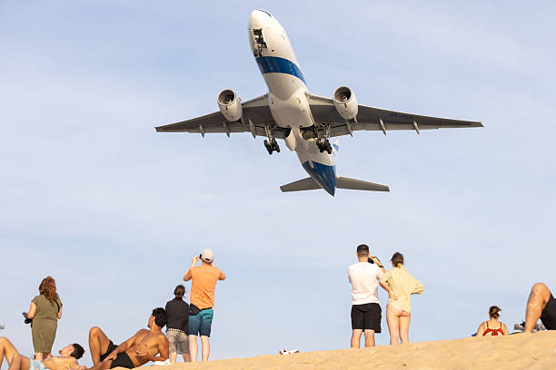 30 December 2025, Mai Khao Beach - Phuket Island.Tourists taking picture with commercial airplane on Mai Khao Beach in Phuket. The area is less crowded than many other beaches in Phuket.