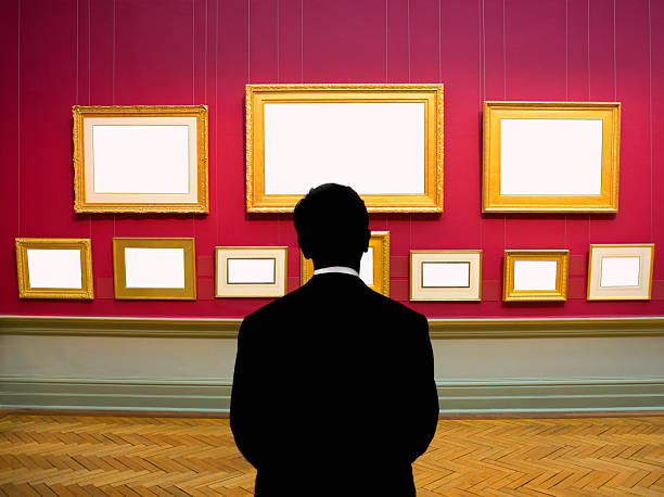 istock Man looking at many blank picture frames hanging on wall 2254839903