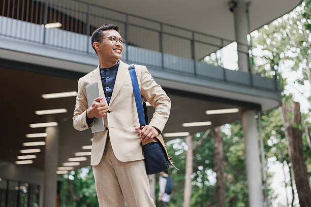 istock Asian businessman holding laptop smiling on modern campus 2254850809