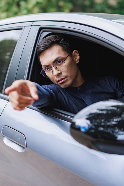 istock Angry driver pointing from car window during road rage 2254850942