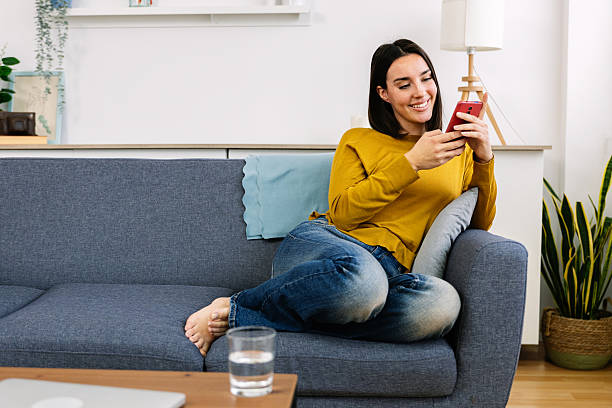 istock Woman relaxing on sofa using smartphone at home 2254858244