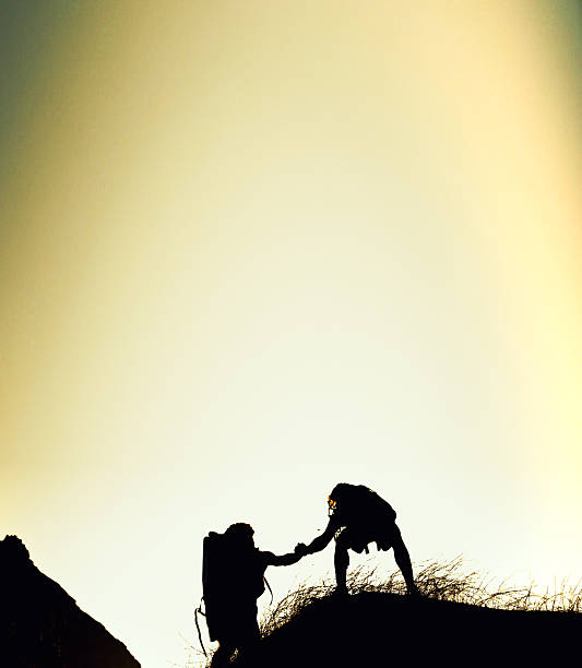 Hiking, silhouette and people on mountain with support, together or motivation for exploration goals. Adventure, space or friends outdoor with climb, endurance or helping hand for trekking milestone.