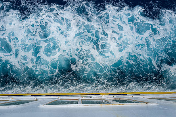 Overhead perspective of a ship deck with vibrant turquoise and white foam churning in the Mediterranean Sea below. Crisp water textures and geometric deck lines create a striking contrast.