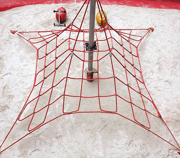High angle view of a smiling little girl having fun while jumping on a rope bridge outdoors.