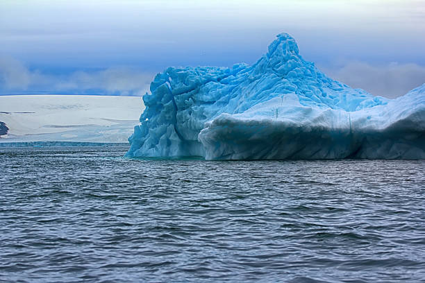 Dark harsh Arctic in high latitudes. Glaciers, snowfields, pierced by wind and water icebergs, lifeless rock, heavy snow clouds and ice fog