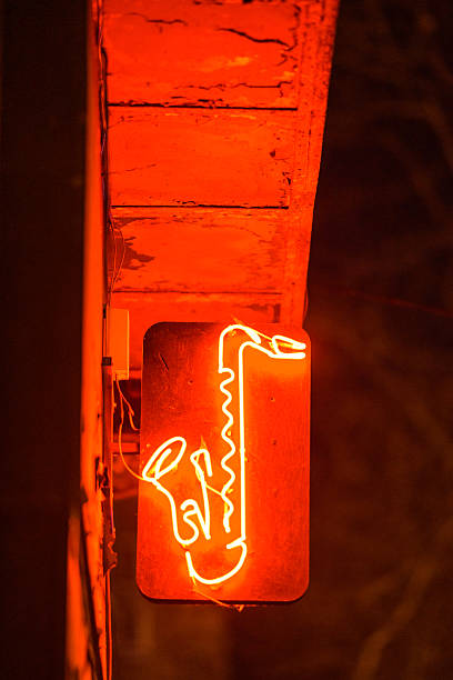 Neon saxophone sign glowing in a dimly lit urban setting.