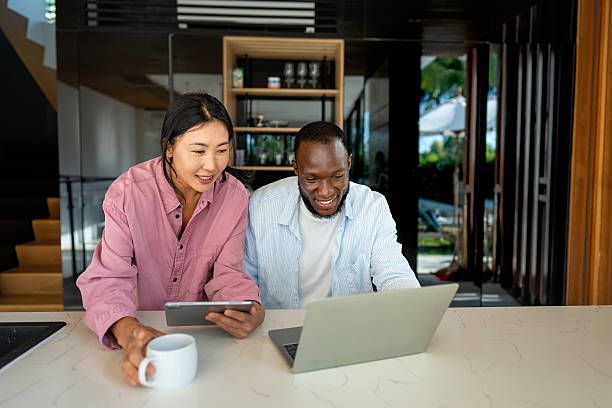 istock Young happy multiethnic couple having fun while using laptop, digital device at home 2254864582