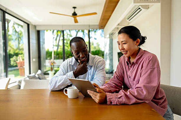 istock Multinational couple enjoying their morning routine, smiling and using laptop and tablet at home 2254864650