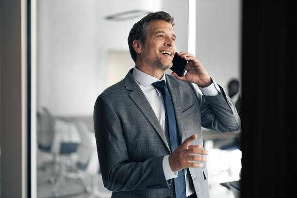 istock Businessman smiling while talking on mobile phone in office 2254869305