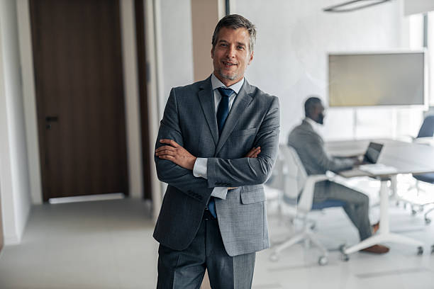 istock Businessman smiling with arms crossed in modern office 2254869341