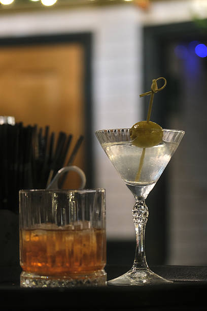 istock Elegant cocktails at a dimly lit bar, featuring a crystal martini with olive garnish beside a classic whiskey drink. 2254870079