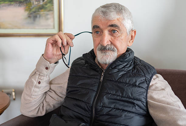 Thoughtful Senior Man Sitting Alone At Home And Looking Away