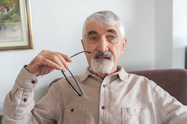 Thoughtful Senior Man Sitting Alone At Home And Looking Away