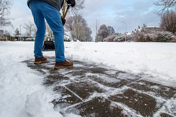 the 76 year old senior is clearing the snow from the sidewalk near the front door in his hometwown Hoofddorp Haarlemmermeer