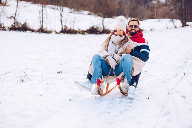 istock Happy couple sledding down a snowy hill in winter 2254881966