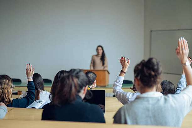 istock College students raising their hands on a class at lecture hall. 2254891915