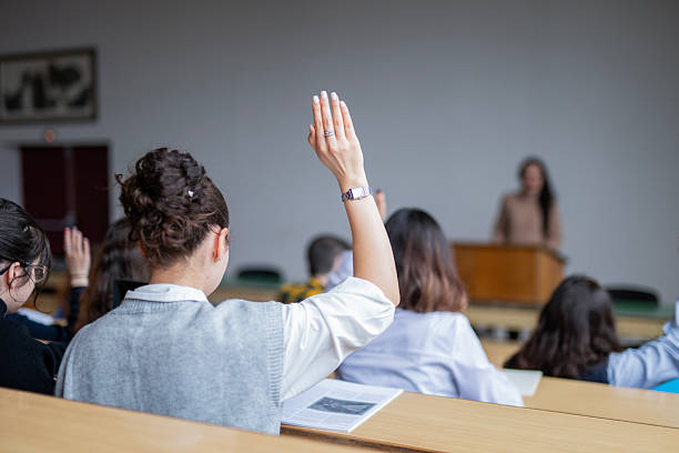 istock College students raising their hands on a class at lecture hall. 2254891949
