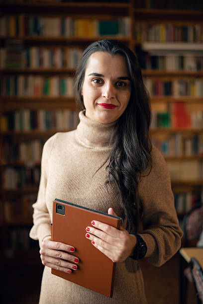 istock Female librarian holding digital tablet in library. 2254891978