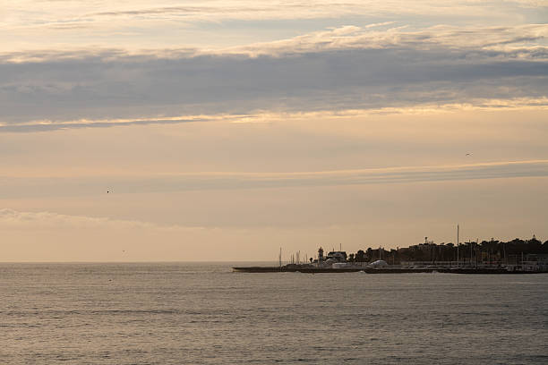 View of the Atlantic Ocean and Estoril marina with boats and coastal buildings under a layered winter sky.