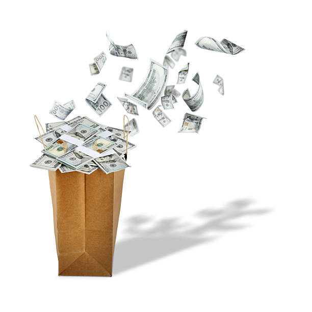 istock Money flying into paper bag against white background 2254896166